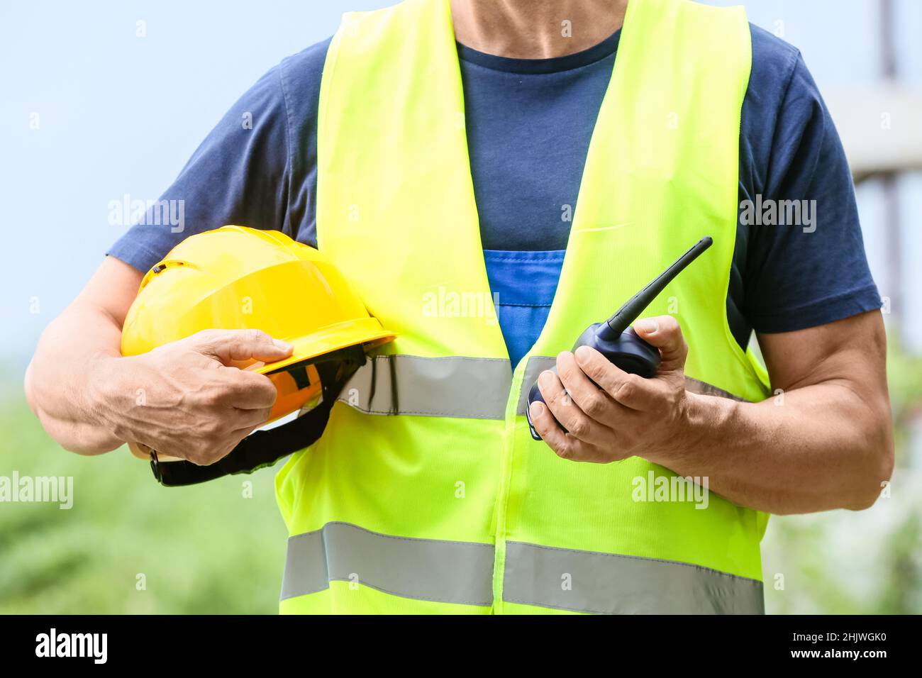 Male worker with safety hardhat and radio transmitter at construction ...