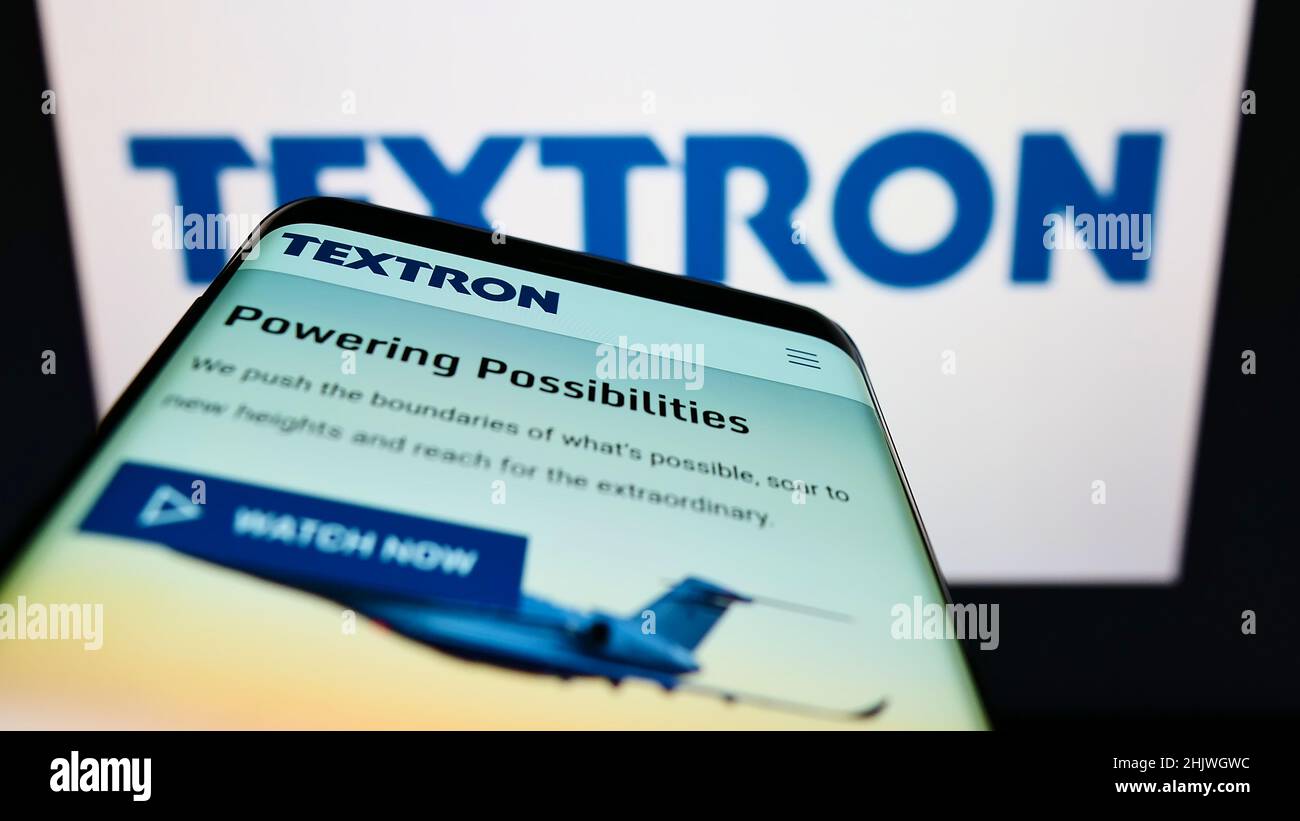 Smartphone with website of US aerospace company Textron Inc. on screen in front of business logo. Focus on top-left of phone display. Stock Photo