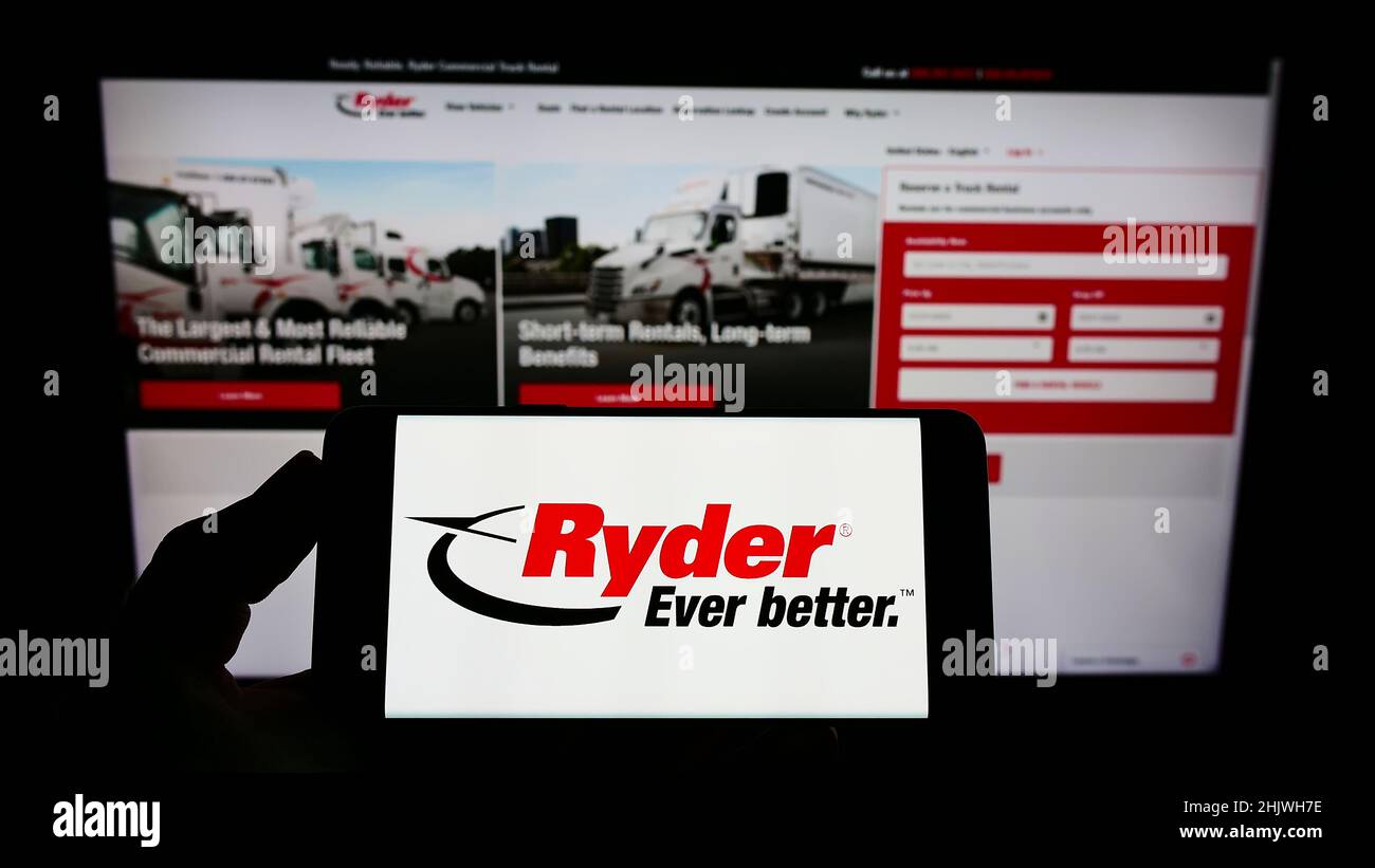 Person holding smartphone with logo of US transportation company Ryder System Inc. on screen in front of website. Focus on phone display. Stock Photo