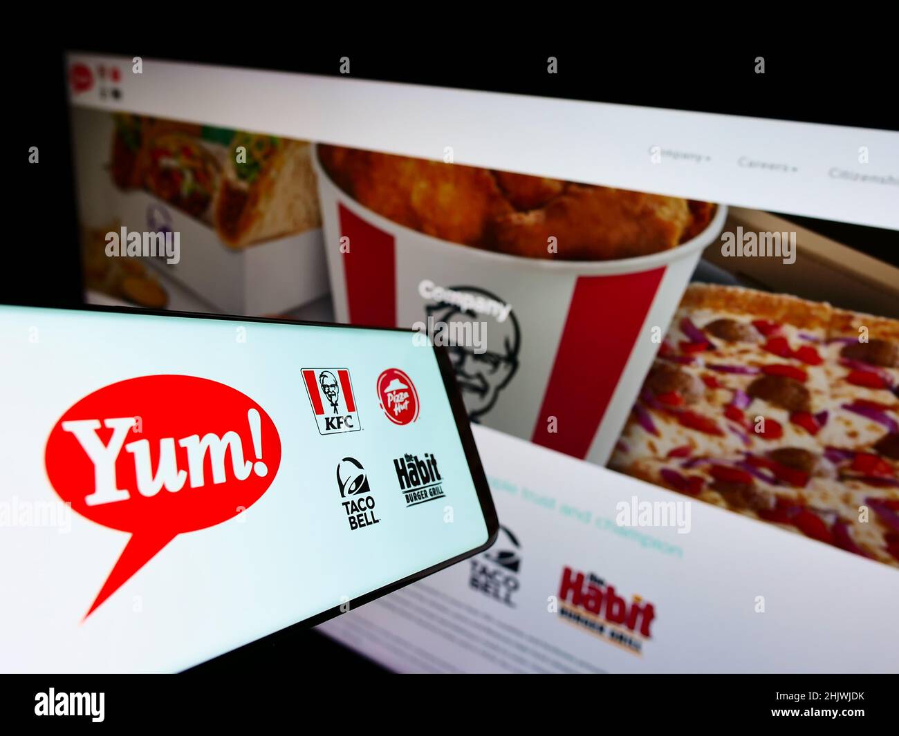 Smartphone with logo of American fast food company Yum! Brands Inc. on screen in front of website. Focus on center-right of phone display. Stock Photo