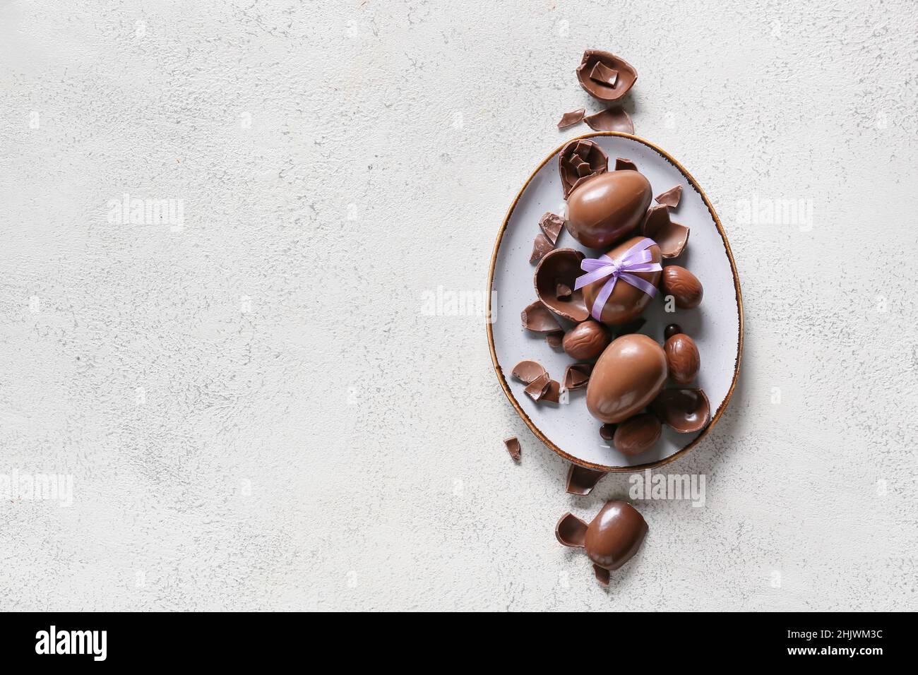 Plate with chocolate Easter eggs on light background Stock Photo