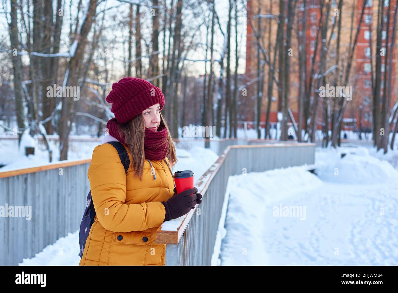 young woman walks in a winter park with a cup of coffee in her hands Stock Photo