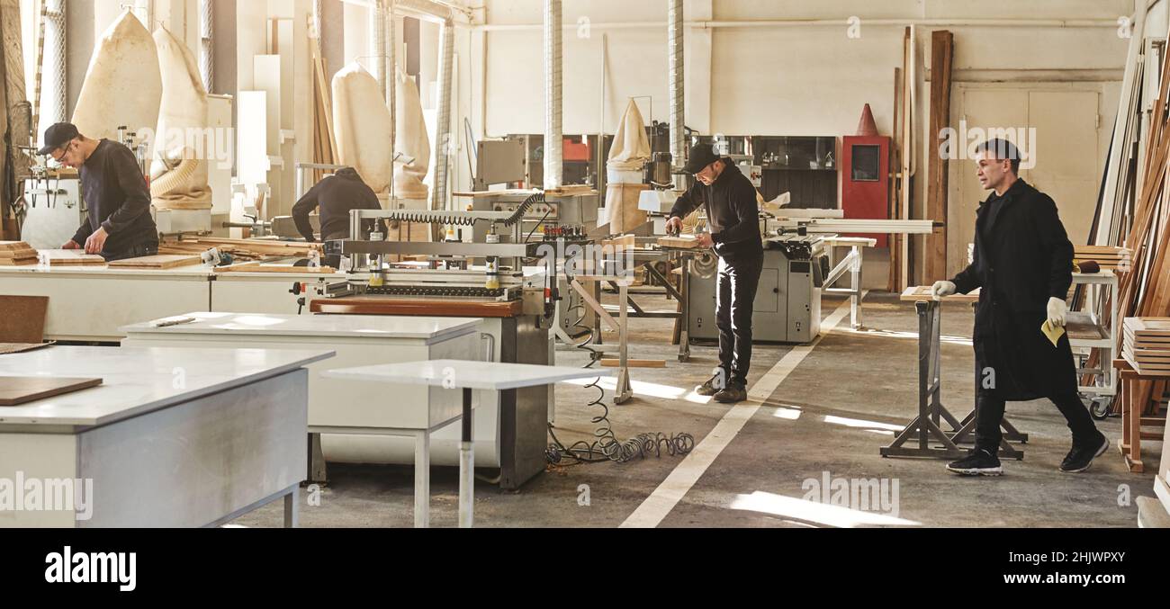 Carpenters working with equipment in carpentry shop. Horizontal shot Stock Photo