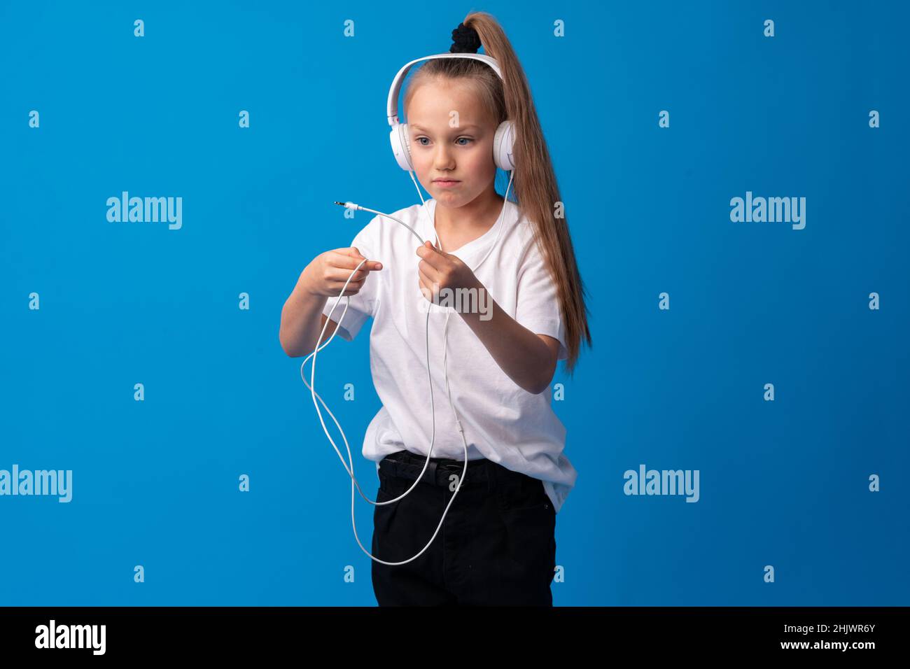 Little girl child wear headphones listen to music over blue background