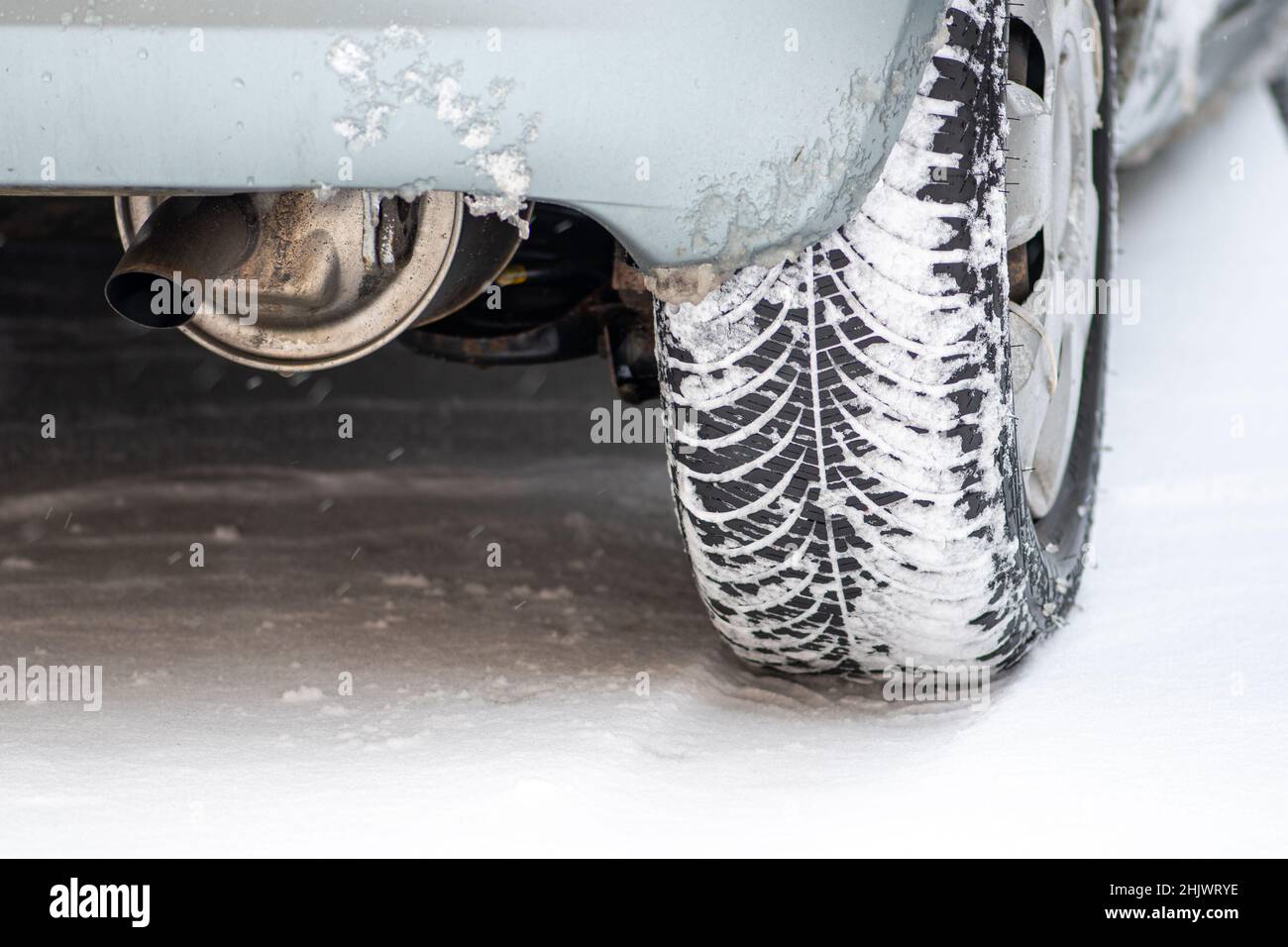 Close up winter tire of a car on the road covered by snow and ice