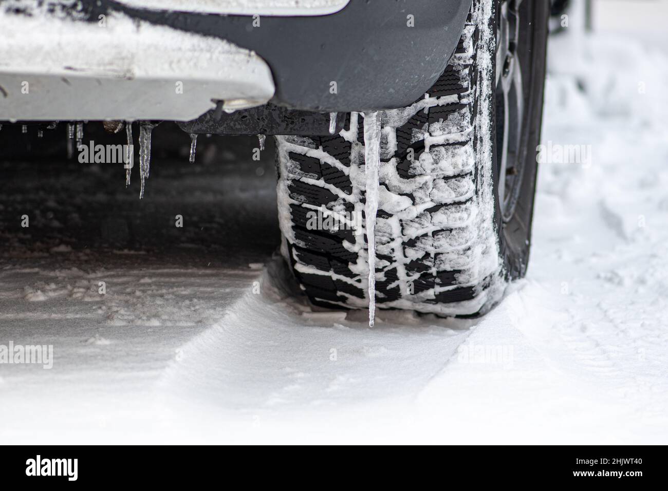 Close up winter tire of a car on the road covered by snow and ice