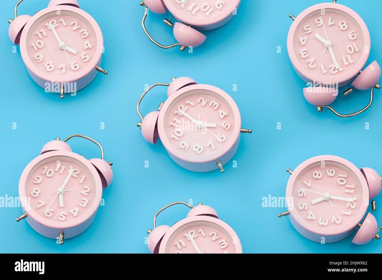 Nostalgia repetitive wallpaper and passing of time concert with minimalist seamless pattern layout of pastel pink mechanical alarm clock isolated on v Stock Photo