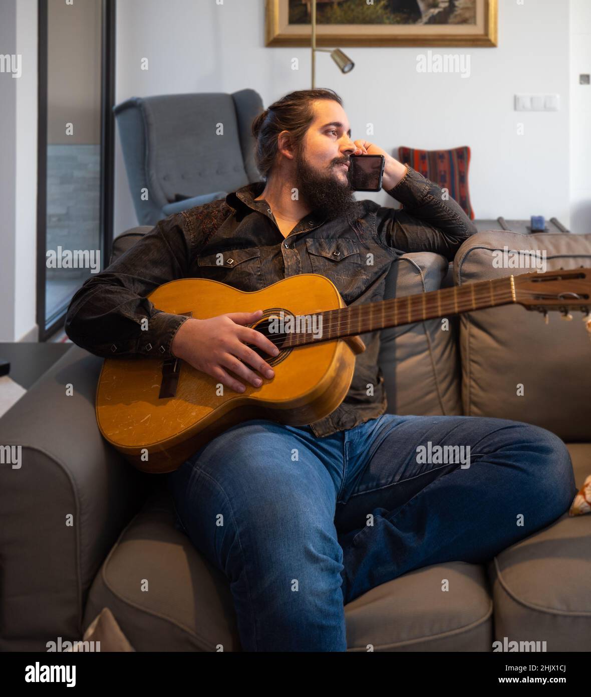 young man talking on the phone to his music producer while holding a guitar Stock Photo