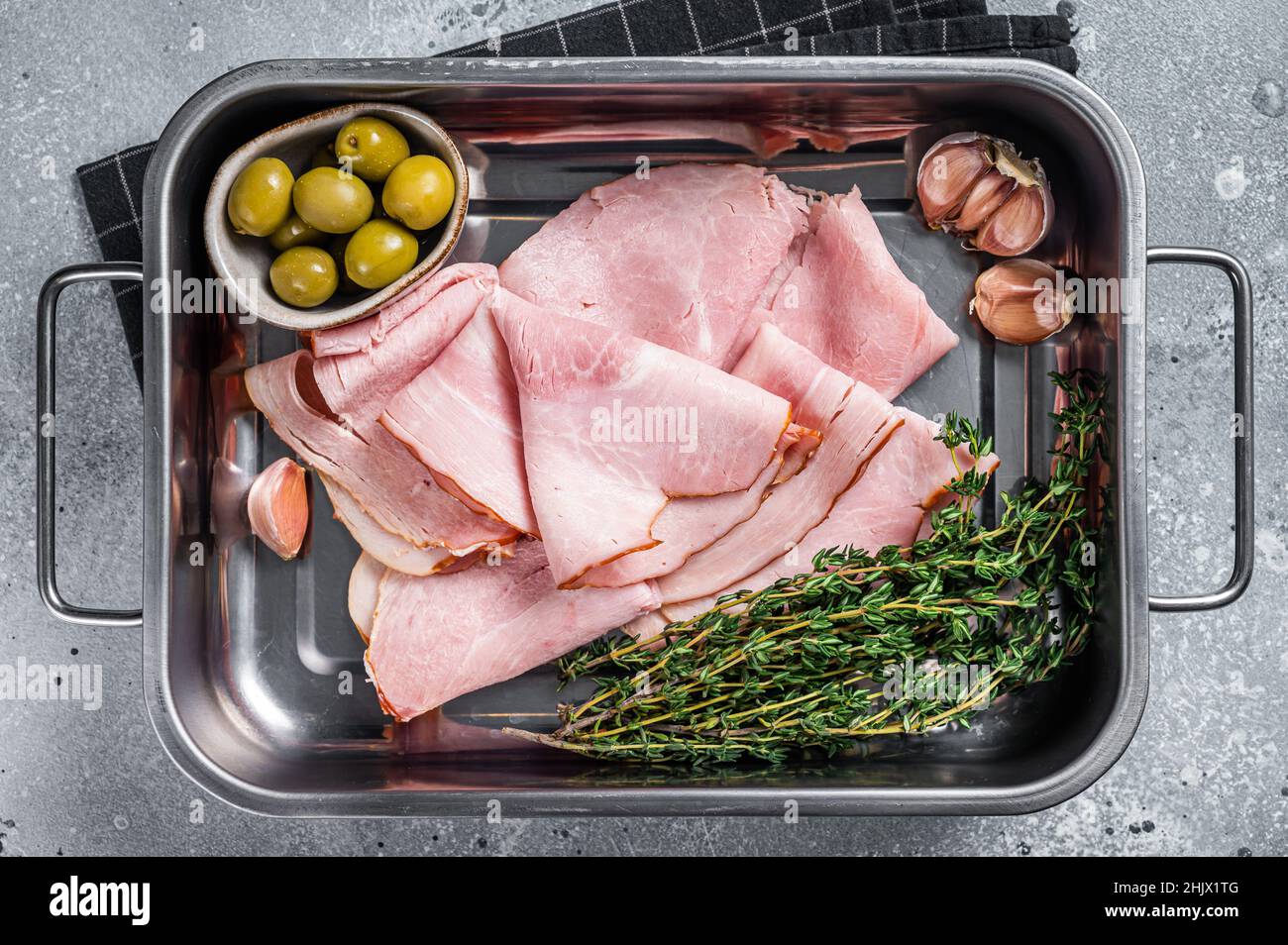 Ham slices in kitchen tray with herb and olives, Italian Prosciutto cotto. Gray background. Top