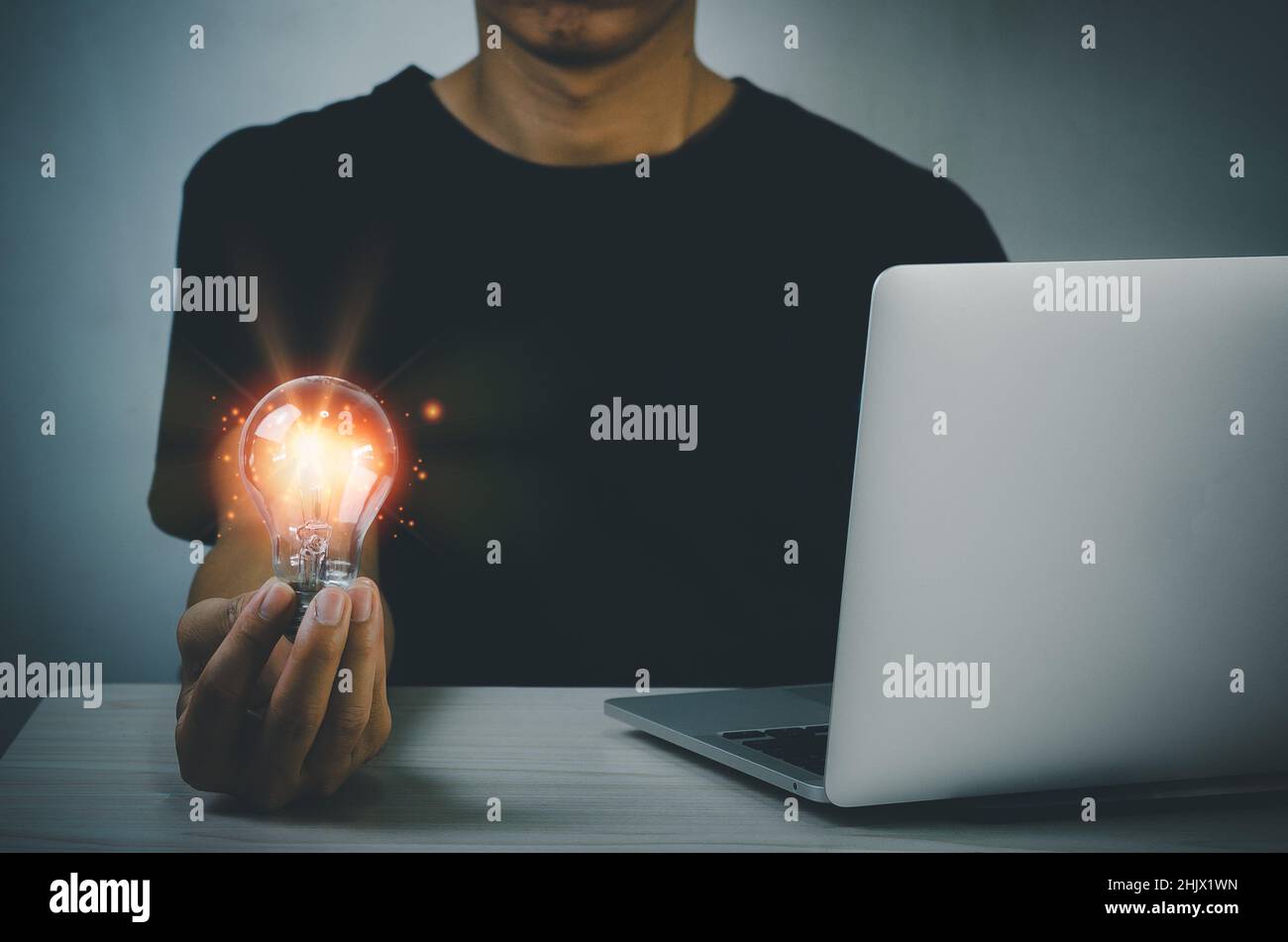 hand holding light bulb ideas Great inspiration and innovation on desk with computer laptop. Stock Photo