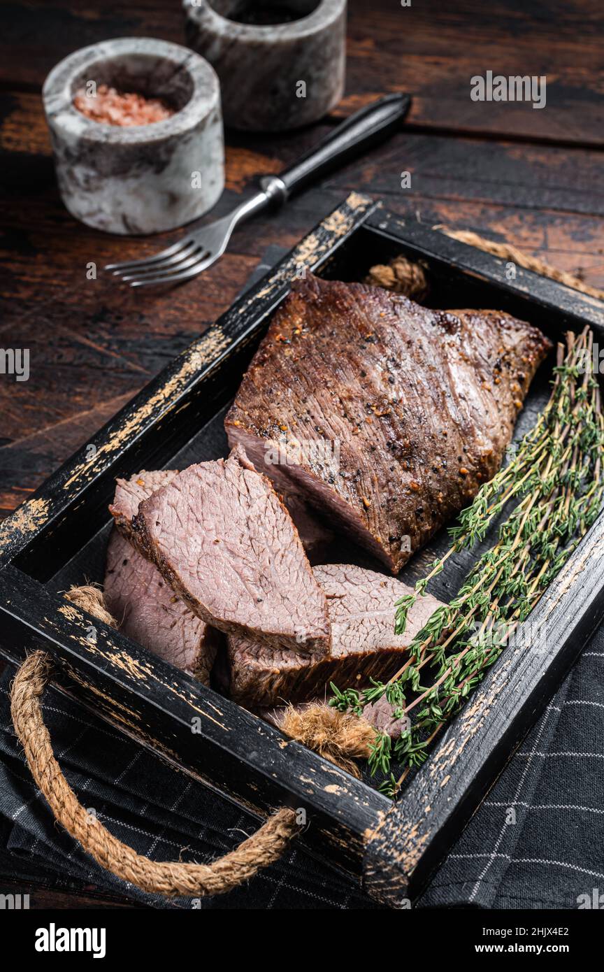 Grilled Tri Tip steak, sirloin bottom beef in a tray with herbs. Wooden