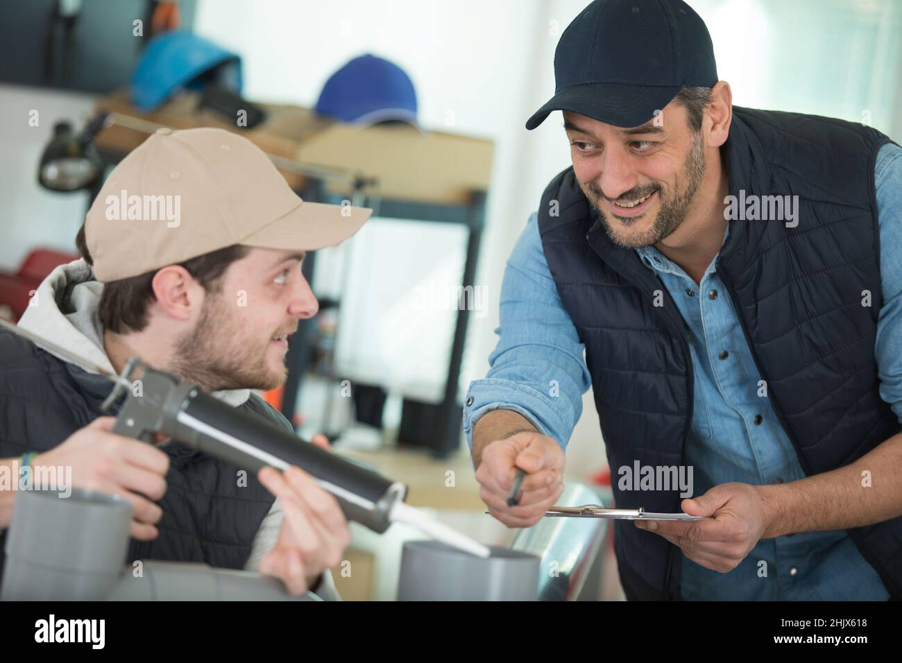 Window Apprentice apprentice being advised how to apply caulk to window Stock Photo - Alamy