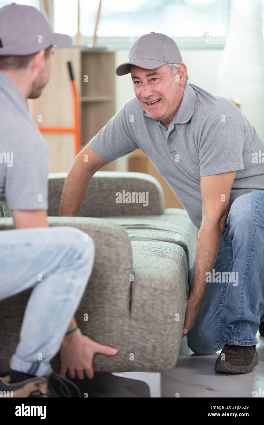 two delivery men in uniform unloading sofa Stock Photo