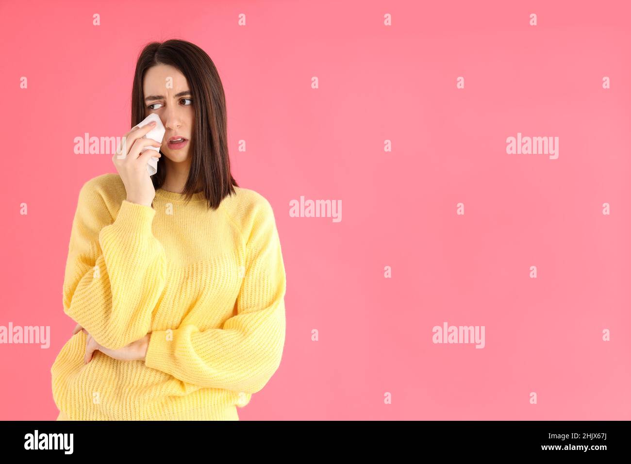 Crying girl in yellow sweater on pink background Stock Photo Alamy