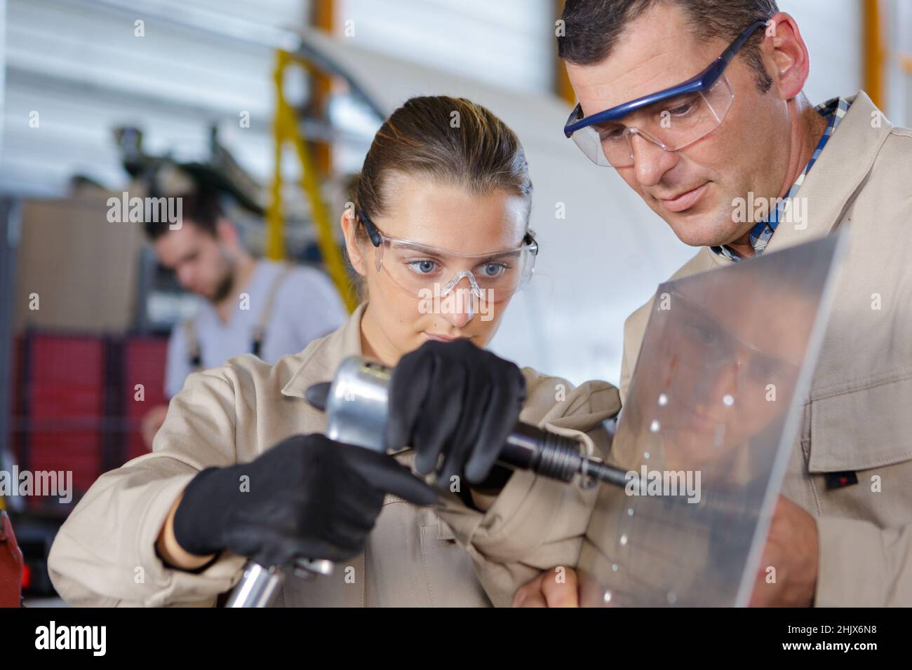 female trainee using machine on sheet metal Stock Photo
