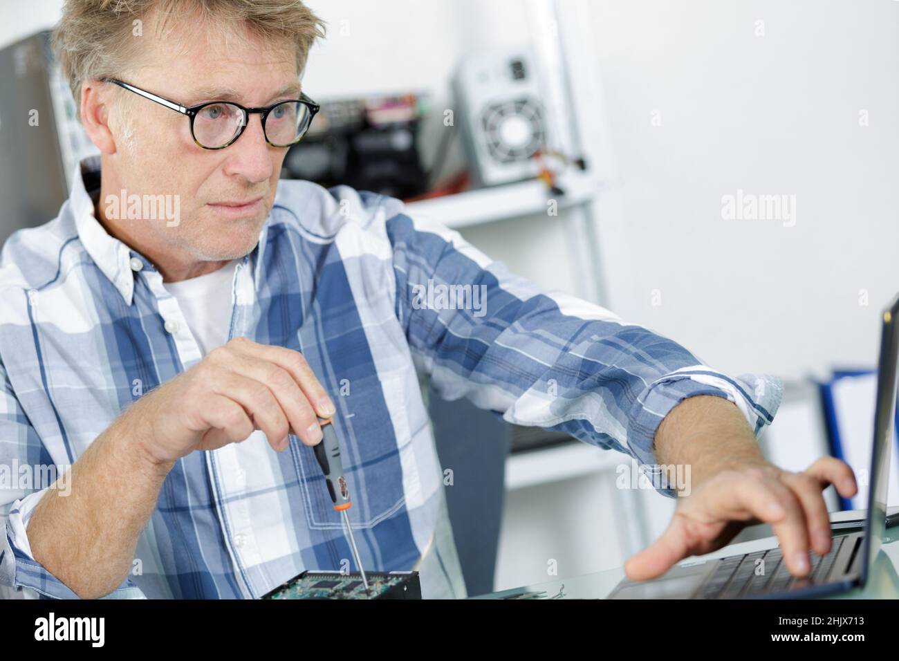 computer repairman installing new hard disk drive in laptop Stock Photo