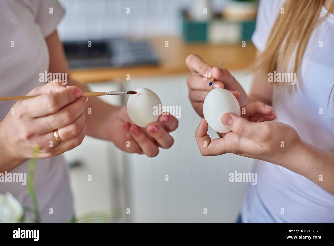Hands with brush painting eggs for easter holiday. Stock Photo