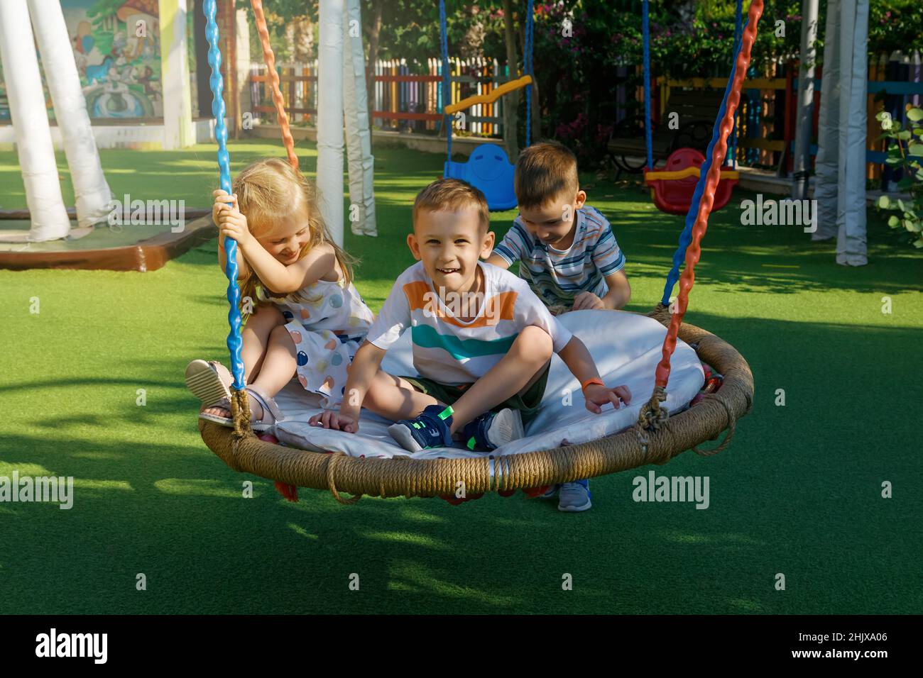 On sunny summer day, children swing on a swing in a playground in a ...