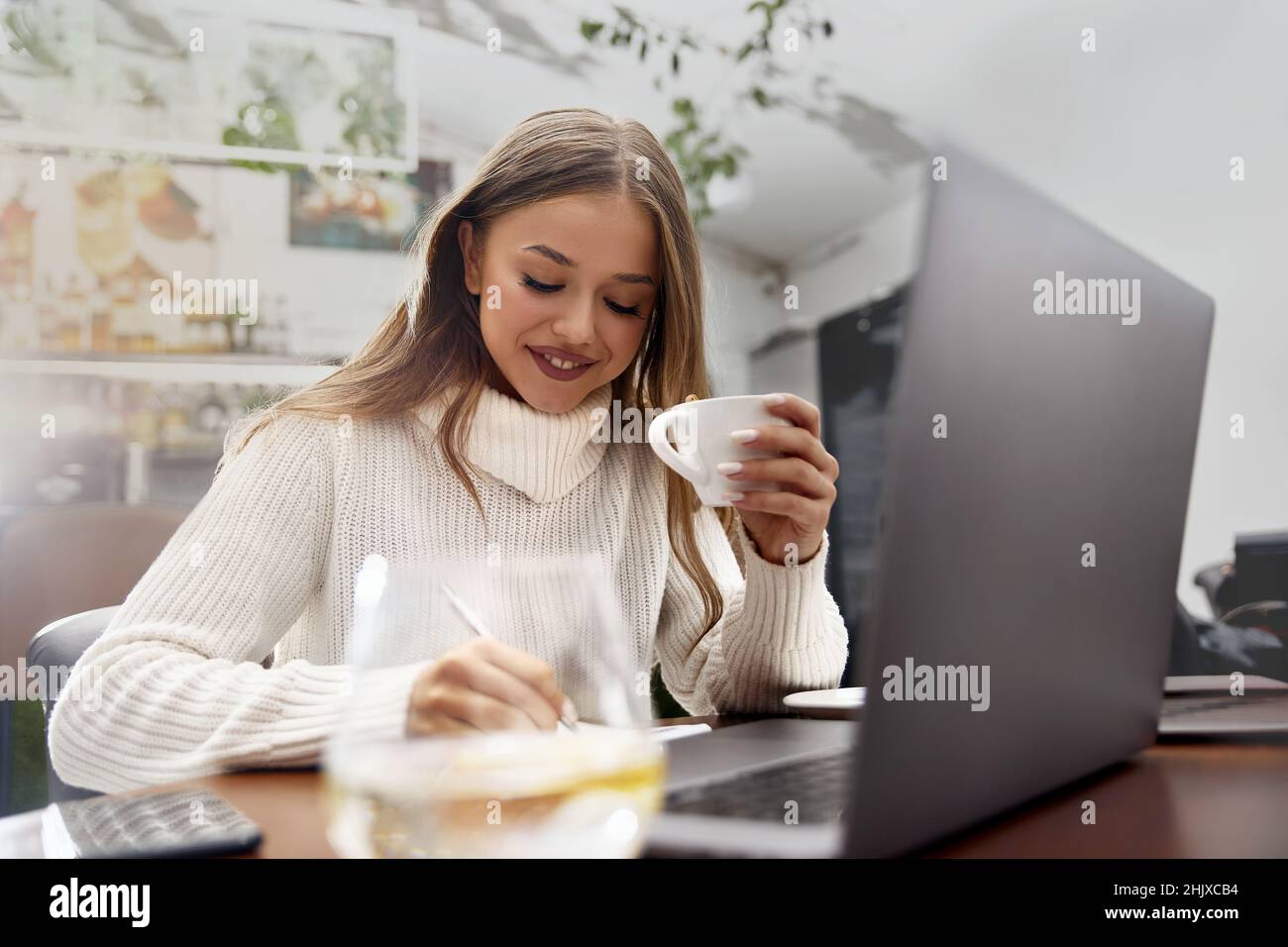Beautiful woman in a cafe drinking coffee and smiling. Stock Photo
