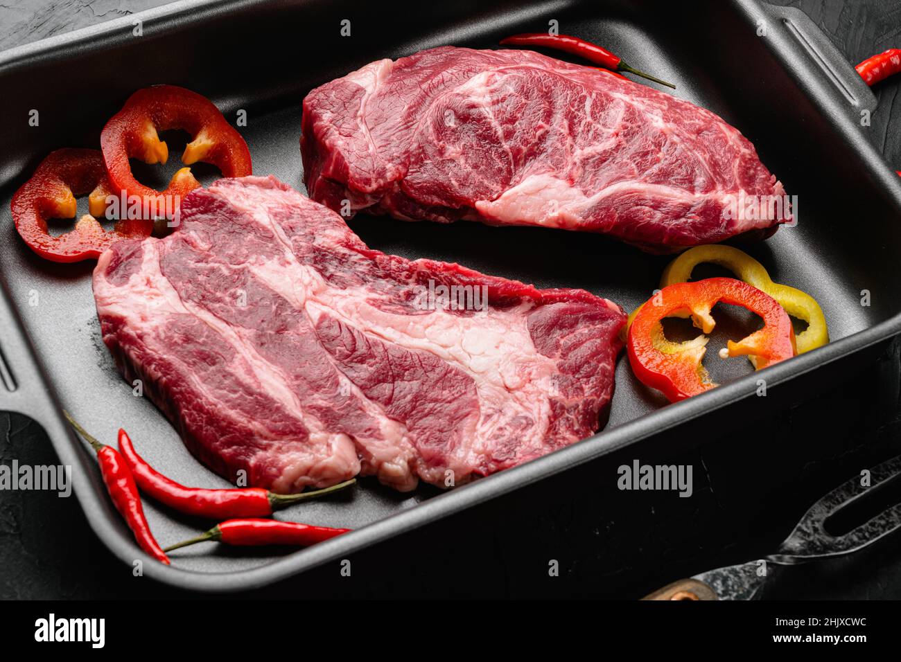 Raw Chuck eye roll steak. Organic beef set, on black dark stone table