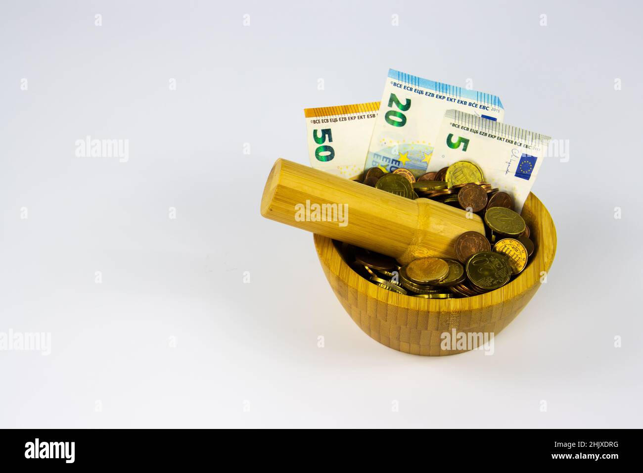 Financial Concept of Inflation - Euro Bills crushed to coins in a mortar grinded by a pestle with copy space Stock Photo
