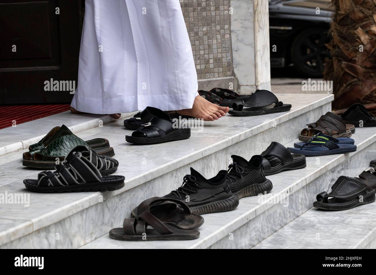 Fragment photo, only legs of arabian man going from mosque after mass. Leg and many shoes outside on the stairs. Shoes of prayers near mosque, islam r Stock Photo