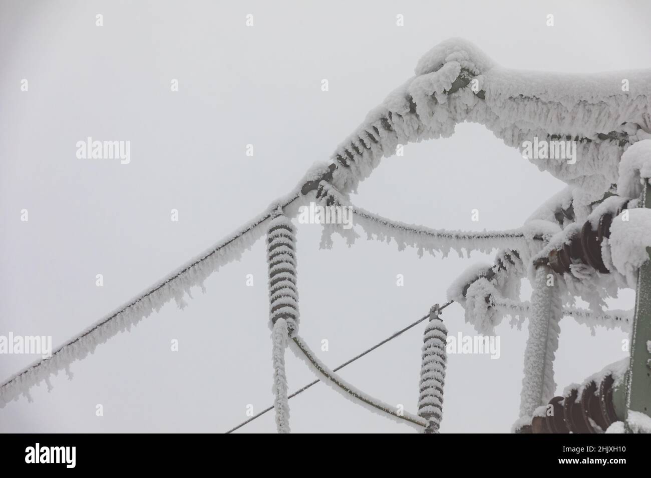 Frozen power line pylons. Hoarfrost on high voltage cables and pylons. Winter in the mountains. Stock Photo