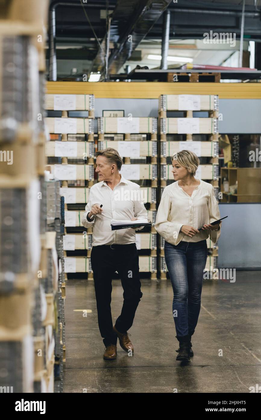 Businessman and female manager walking in factory warehouse Stock Photo