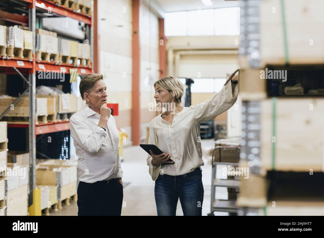 Female manger explaining senior businessman in factory warehouse Stock Photo