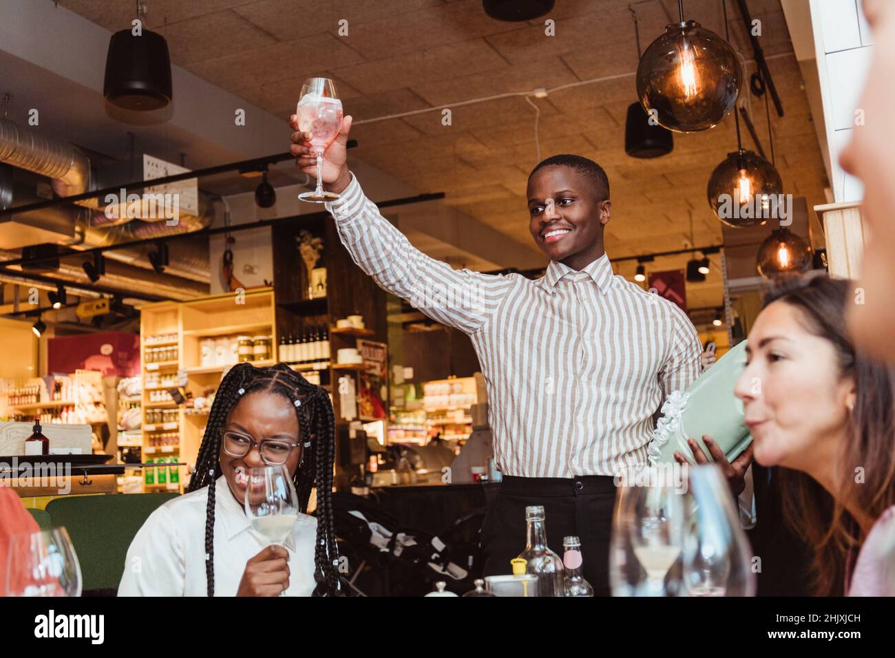 Smiling man holding wineglass by male and female friends during dinner party at bar Stock Photo
