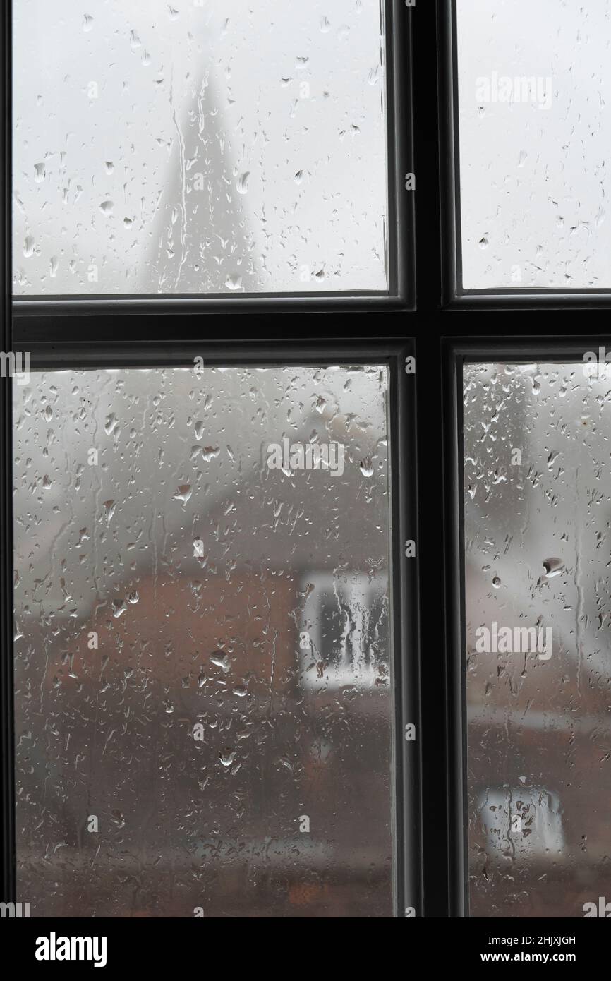 Rain on glass window pane with church spire in background, Burwash, East Sussex, England, United Kingdom, Europe Stock Photo