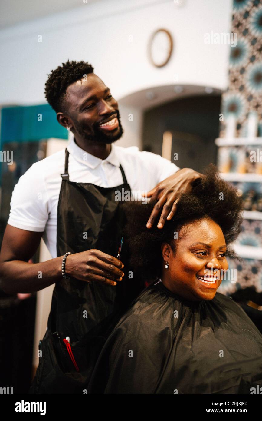 Smiling Male Barber Cutting Hair Of Female Customer In Salon 2HJXJP2 