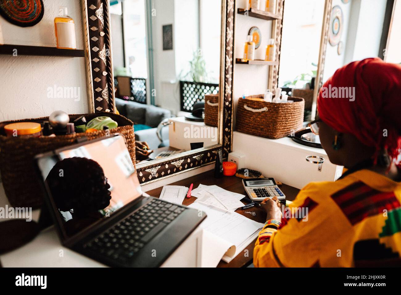 Female hairdresser with laptop at table in barber shop Stock Photo