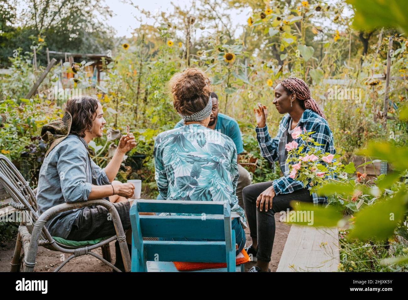 Male and female farmers having coffee while sitting in community garden Stock Photo