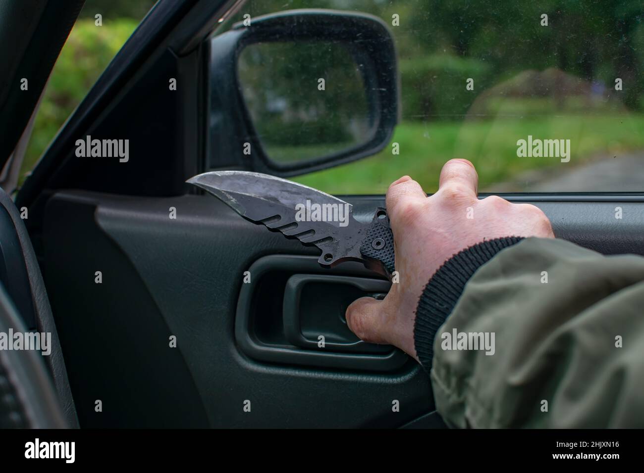 knife in the hand of a man, a bandit who opens the car door Stock Photo