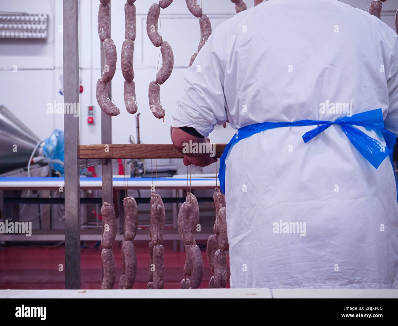 Factory Stuffing worker manufacturing, stuffing and tying pork sausages, salami and ...
