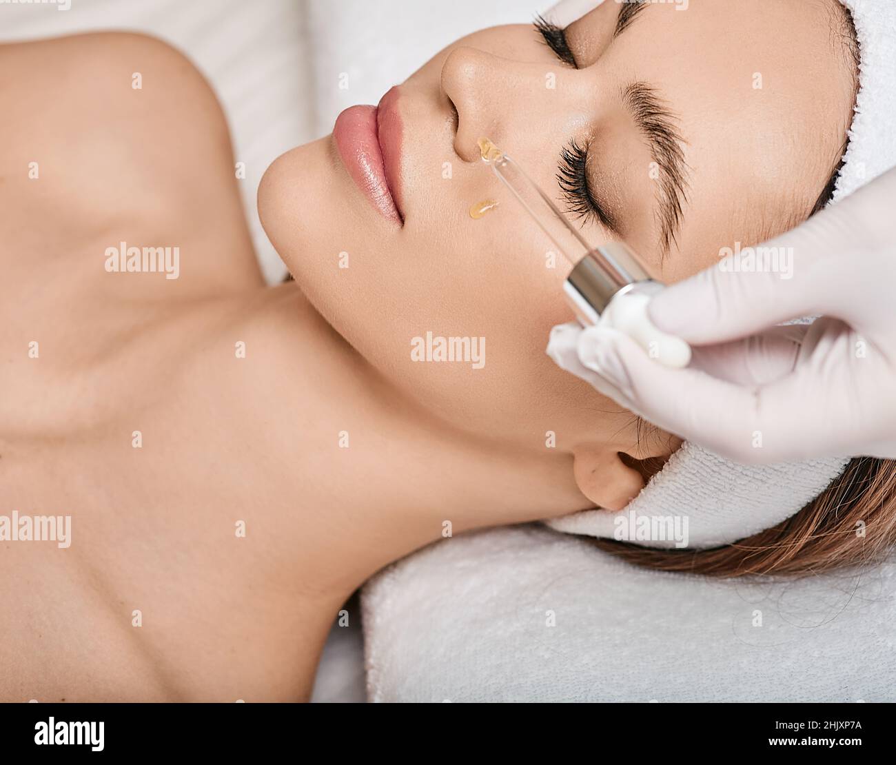 Female patient with closed eyes enjoying cosmetology procedures using treatments oils and serum to facial skin care Stock Photo