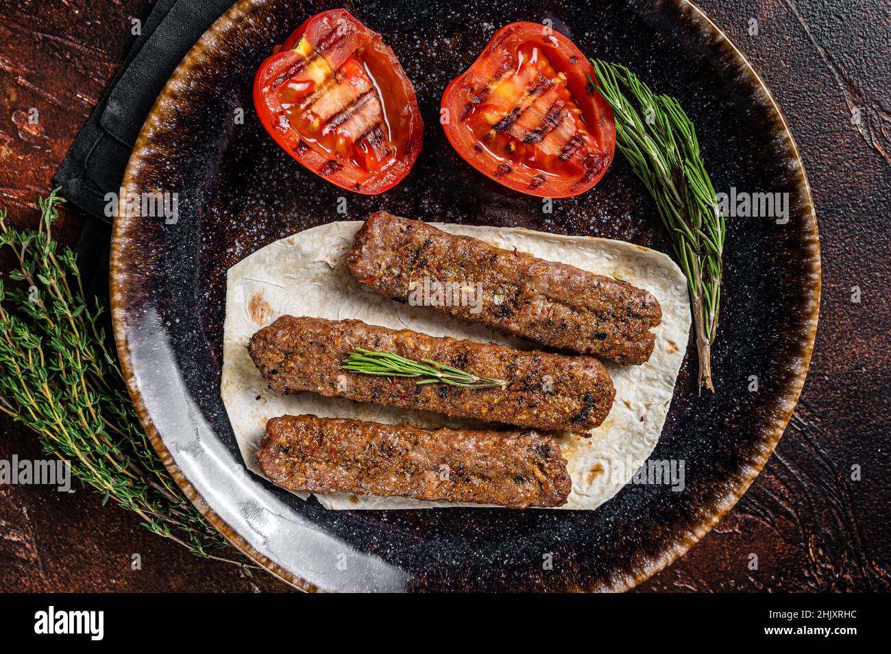 Grilled Urfa shish kebab on a plate with tomato. Dark background. top view  Stock Photo - Alamy