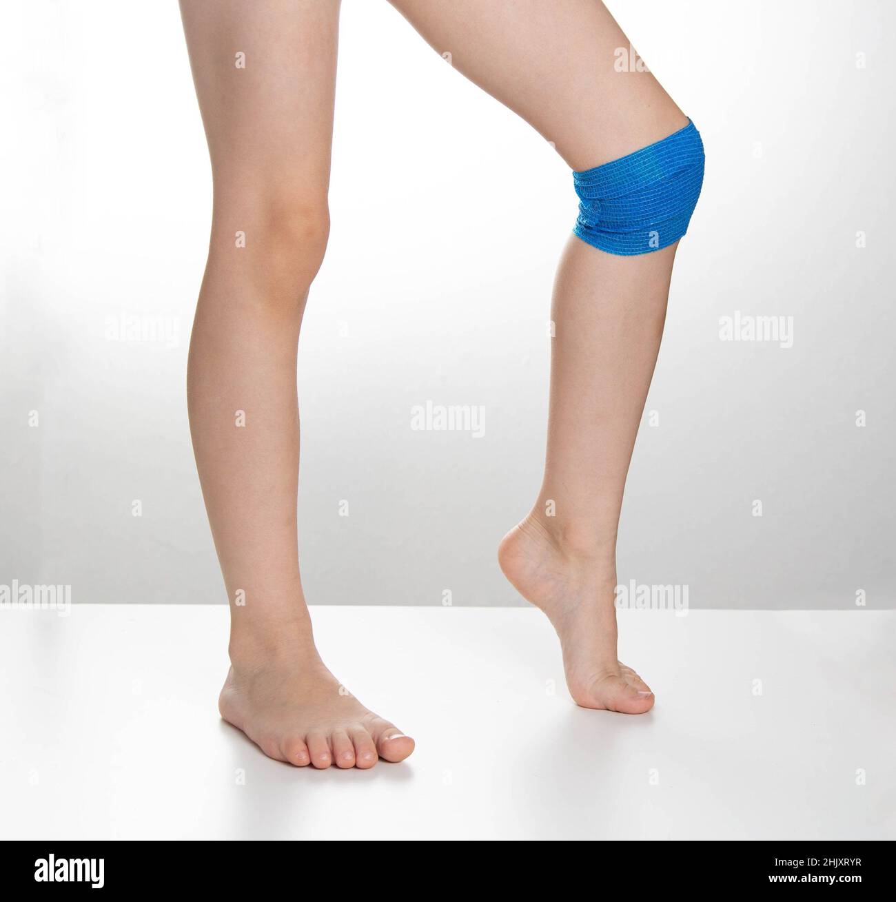 Blue elastic bandage on the knee joint on the child's leg. White background, treatment of knee
