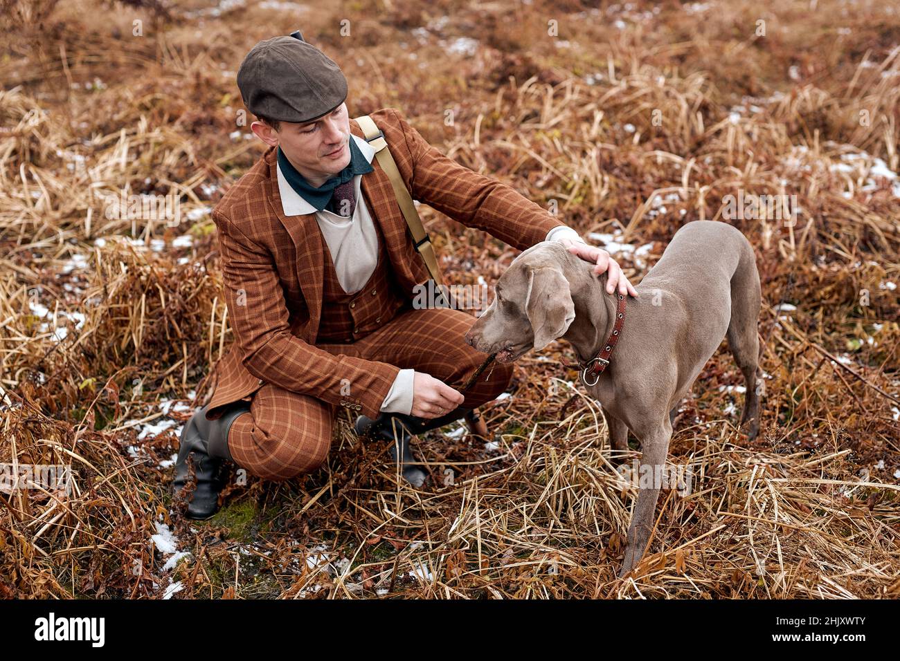 Hunter with gray hunting dog in autumn forest. Image taken during big game hunting trip. Hunting period, autumn season open. handsome caucasian guy in Stock Photo