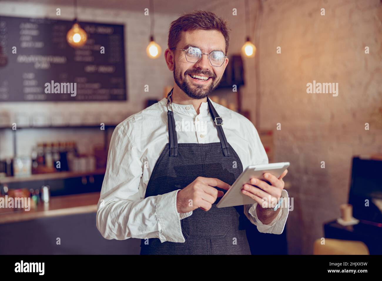 Joyful male worker using tablet computer in cafe Stock Photo