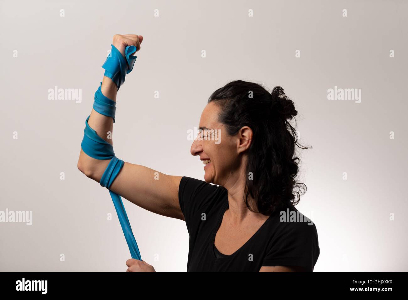 adult Caucasian female with curly brown hair and blue elastic armband on white background Stock Photo