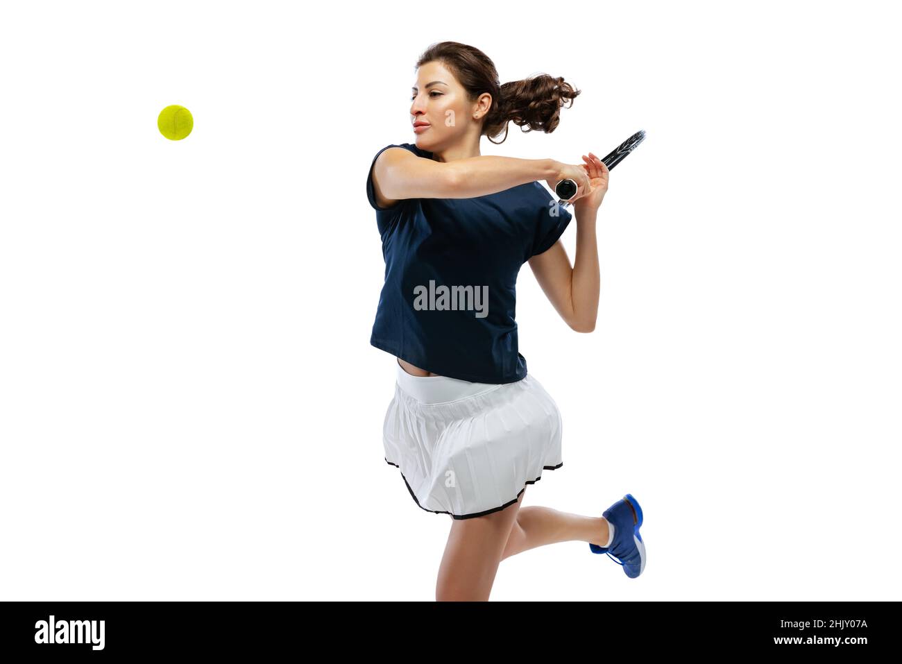 Studio shot of young sportive woman, tennis player training alone isolated on white background. Action, summer sports, fitness, sport concept. Stock Photo