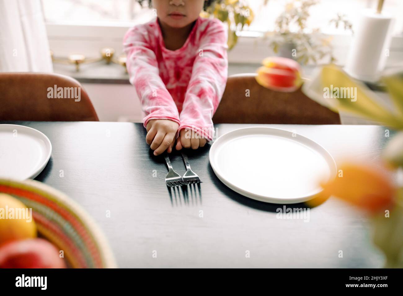 Midsection of girl with forks and plate on table at home Stock Photo