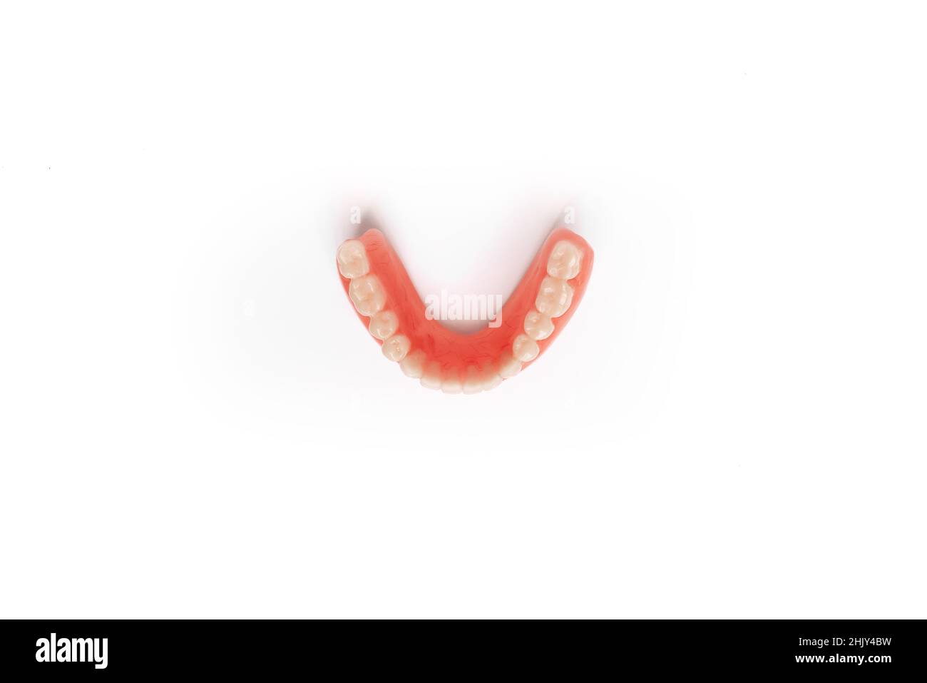 Top view of the lower denture on a white background. Dental prosthesis close-up. Dentures. Isolate on white background. Lower removable plastic prosth Stock Photo