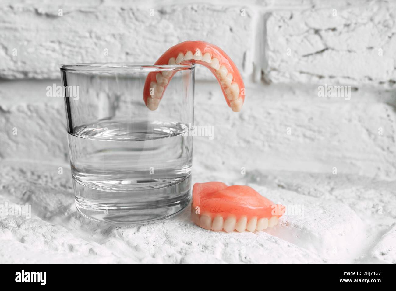 A denture in a glass of water. Dental prosthesis care. Full removable