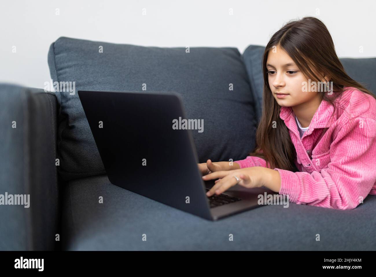 Cute girl sitting on sofa with laptop Stock Photo - Alamy