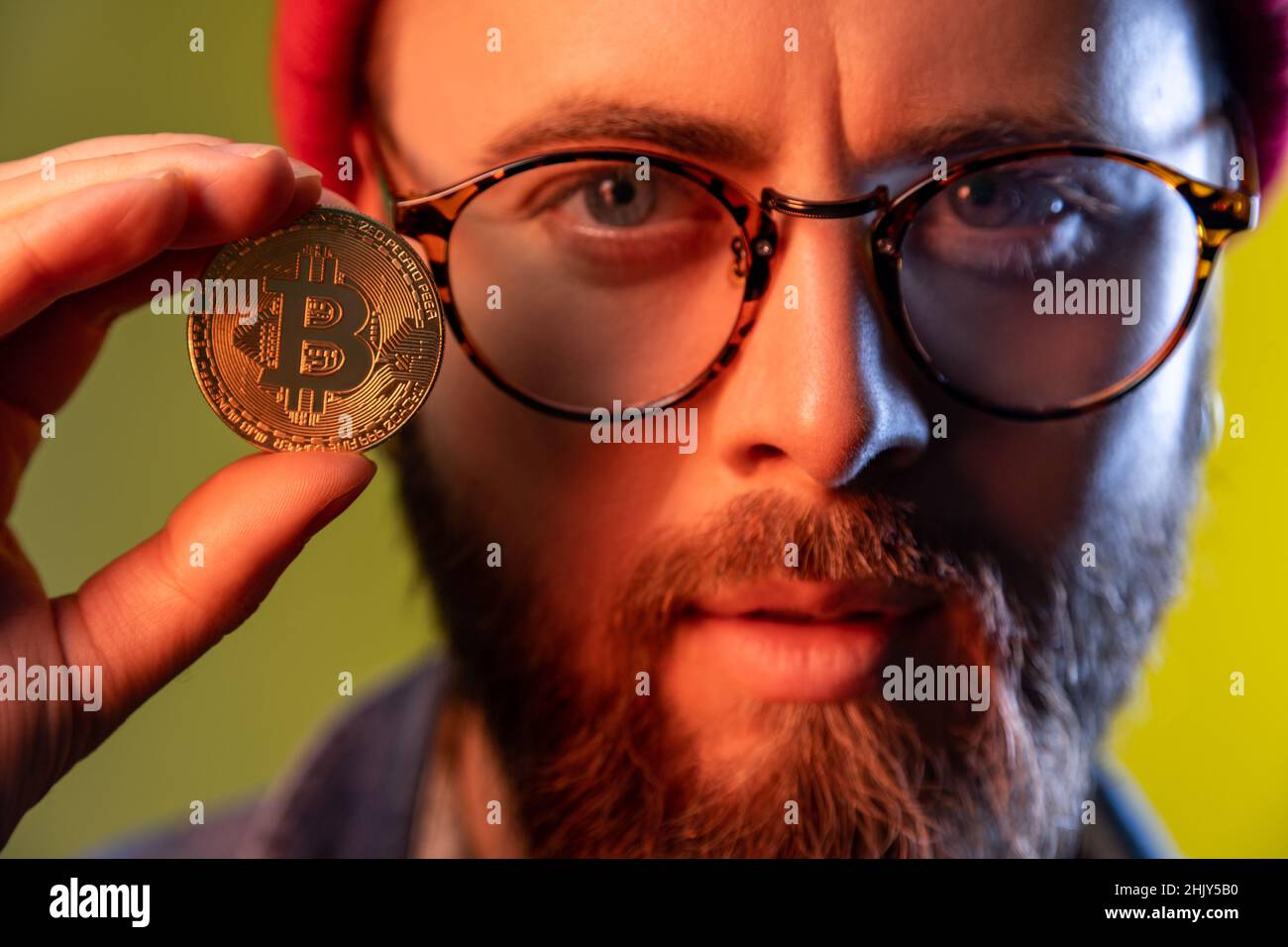 Closeup portrait of serious hipster guy in glasses showing golden coin  bitcoin crypto currency, electronic virtual money. Indoor studio shot  isolated on colorful neon light background Stock Photo - Alamy