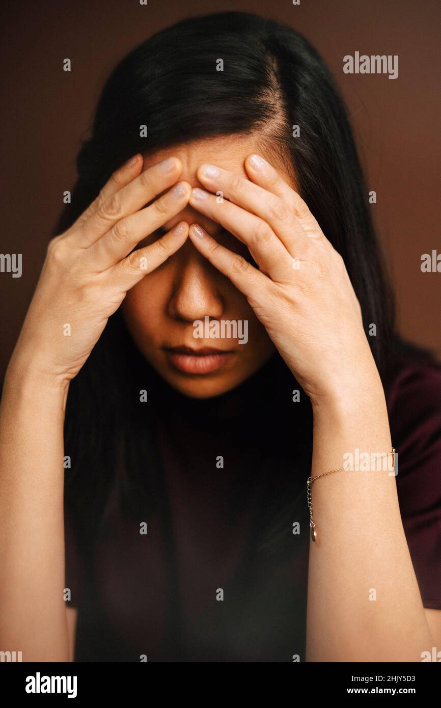 Frustrated woman with head in hands at studio Stock Photo