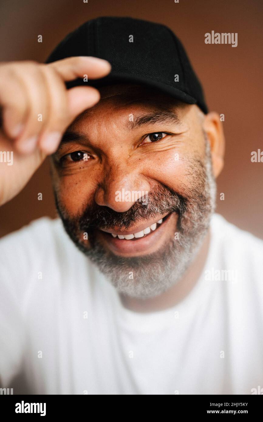 Happy mature man holding cap against brown background Stock Photo